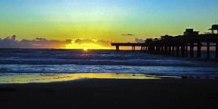 Por do sol no pier de Tramandaí com reflexo no mar